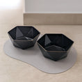 Bild in Galerie-Betrachter laden, Zwei schwarze, sechseckige Porzellan-Futternäpfe für Hunde und Katzen die auf einemrgrauen Napfunterlage stehen, modernes Design mit glänzender Oberfläche.