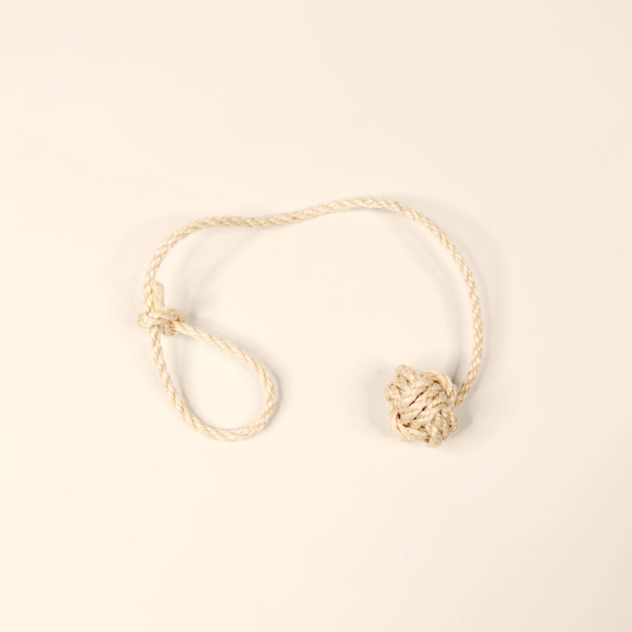 Katzenspielzeug Affenfaust aus naturfarbenem Sisalseil mit Schlaufe und Glöckchen – handgefertigt in Deutschland, nachhaltig und plastikfrei. Beiger Hintergrund