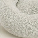 Nahaufnahme eines runden, hellgrauen Hundebett aus weichem Plüsch mit erhöhtem Rand – gemütlicher Schlafplatz für Hunde und Katzen.