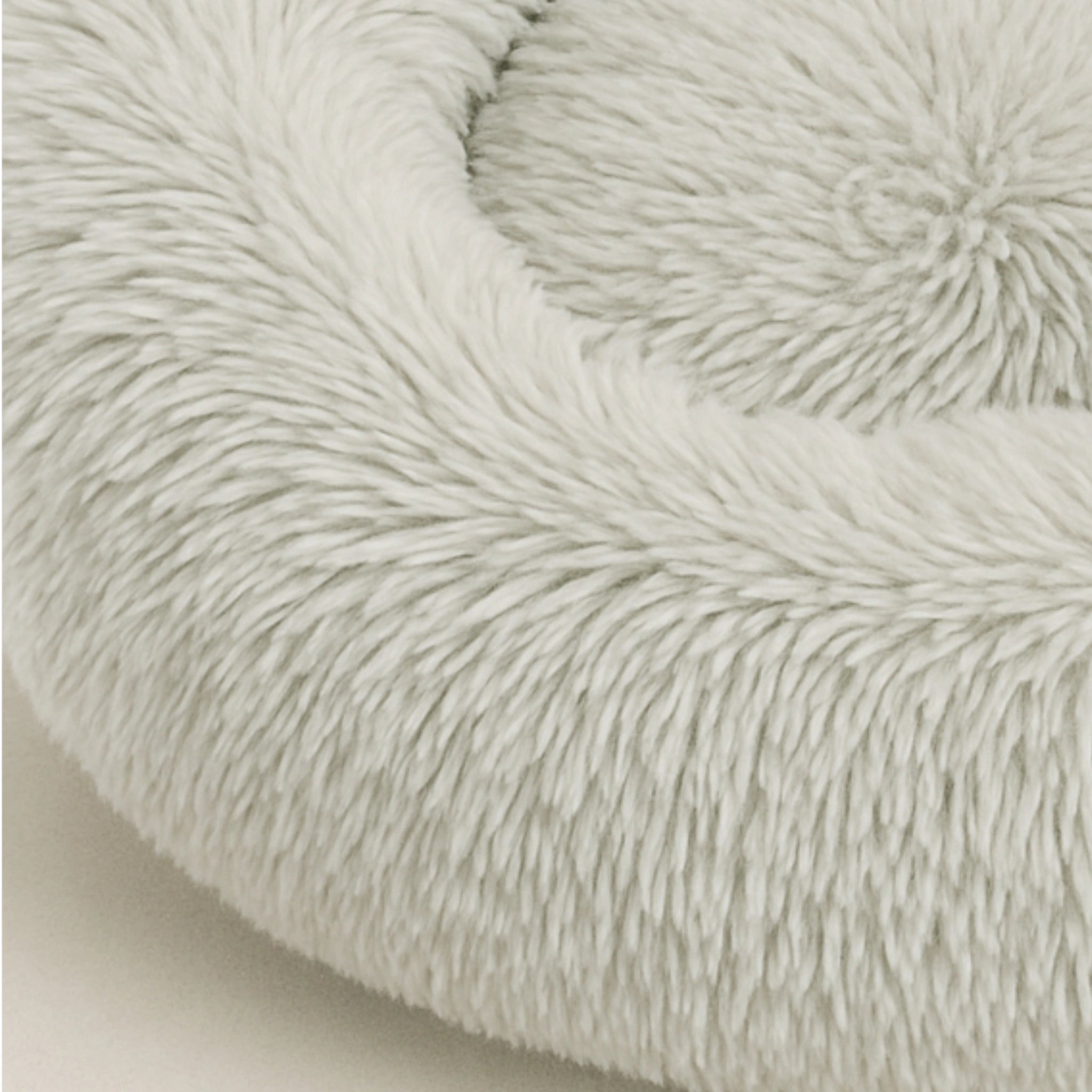 Nahaufnahme eines runden, hellgrauen Hundebett aus weichem Plüsch mit erhöhtem Rand – gemütlicher Schlafplatz für Hunde und Katzen.