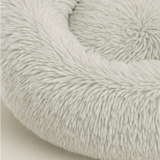 Nahaufnahme eines runden, hellgrauen Hundebett aus weichem Plüsch mit erhöhtem Rand – gemütlicher Schlafplatz für Hunde und Katzen.