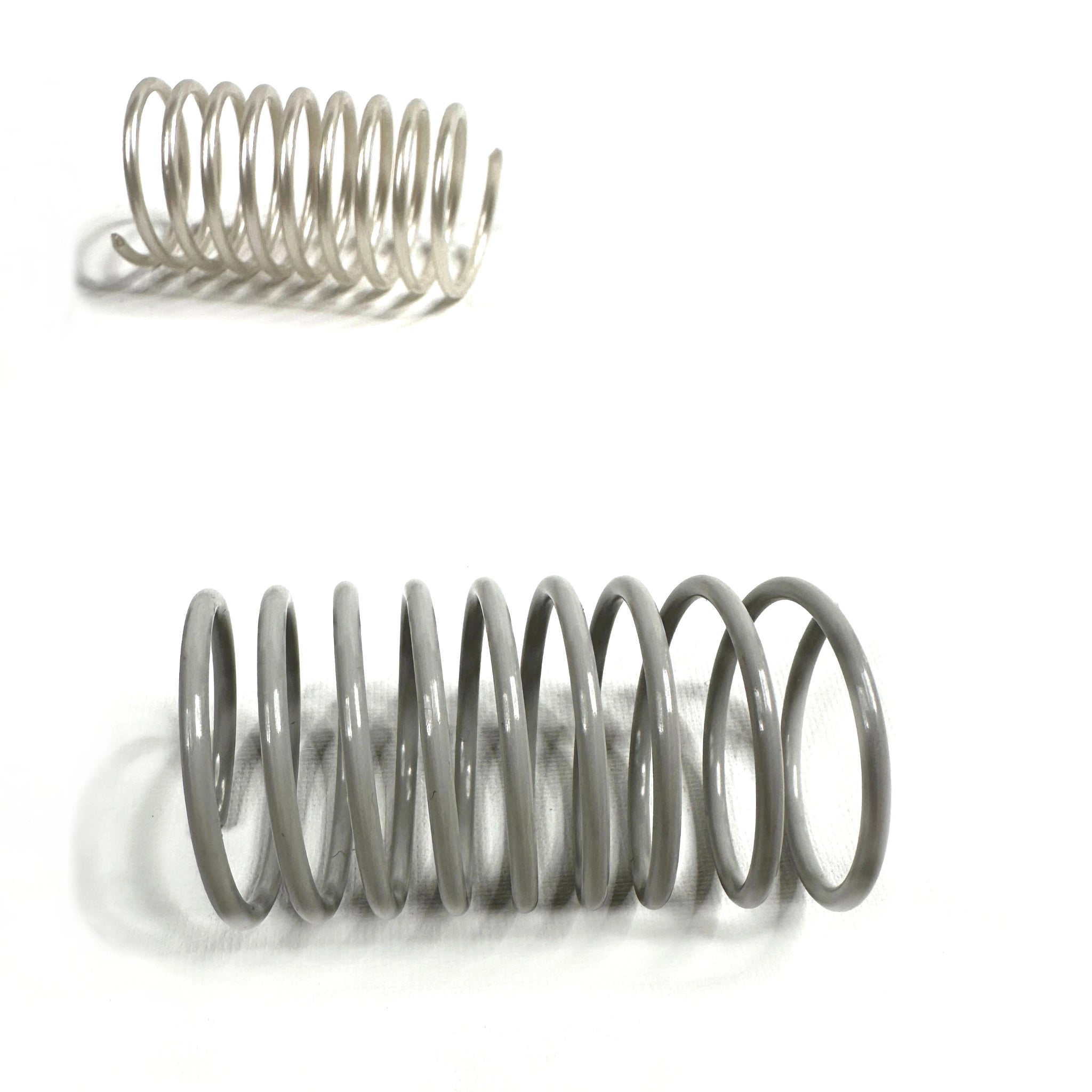 Nahaufnahme zwei Katzenspiralen in Grau und Schwarz – langlebiges, geräuscharmes Katzenspielzeug aus Frankreich im minimalistischen Design.