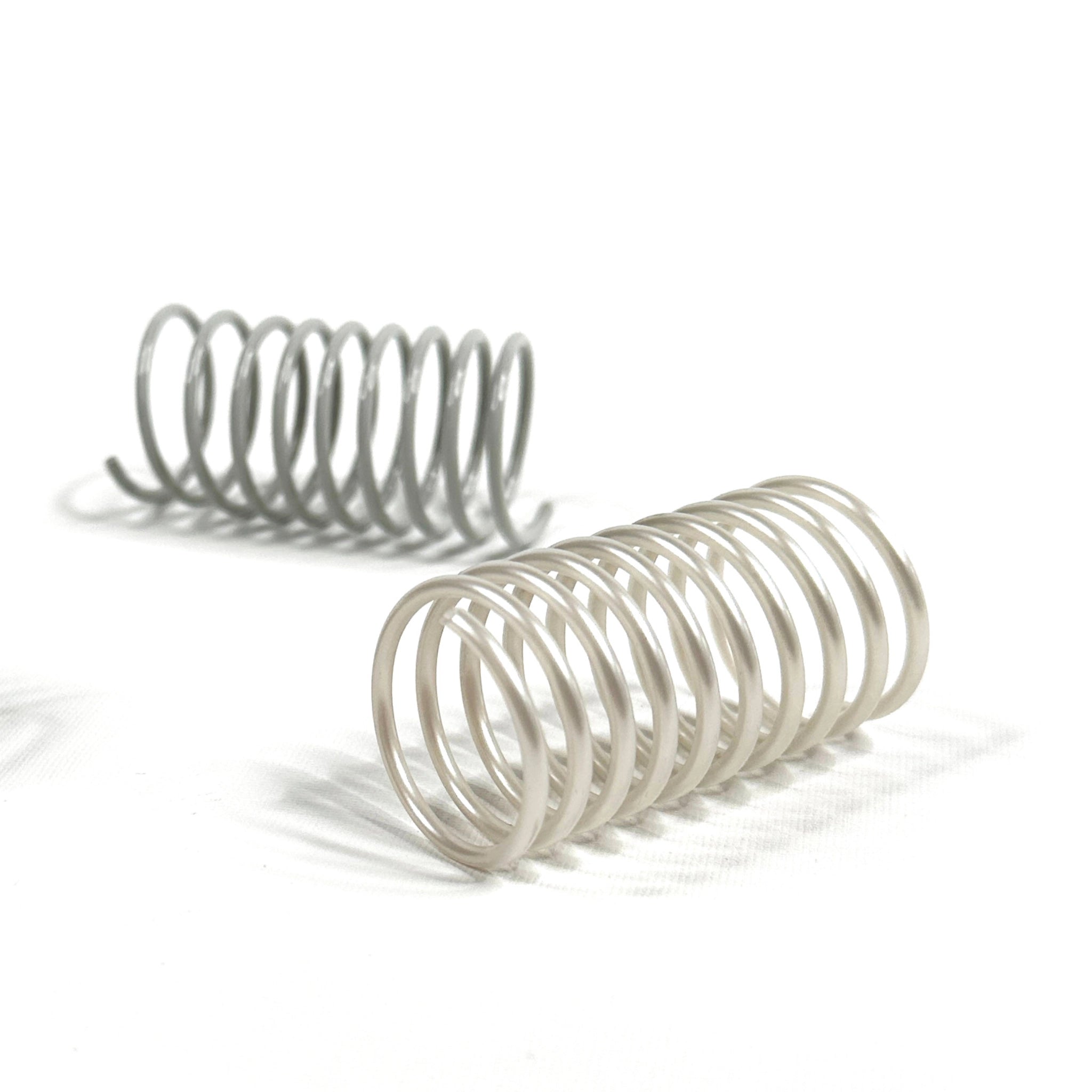 Nahaufnahme zwei Katzenspiralen in Grau und Schwarz – langlebiges, geräuscharmes Katzenspielzeug aus Frankreich im minimalistischen Design.