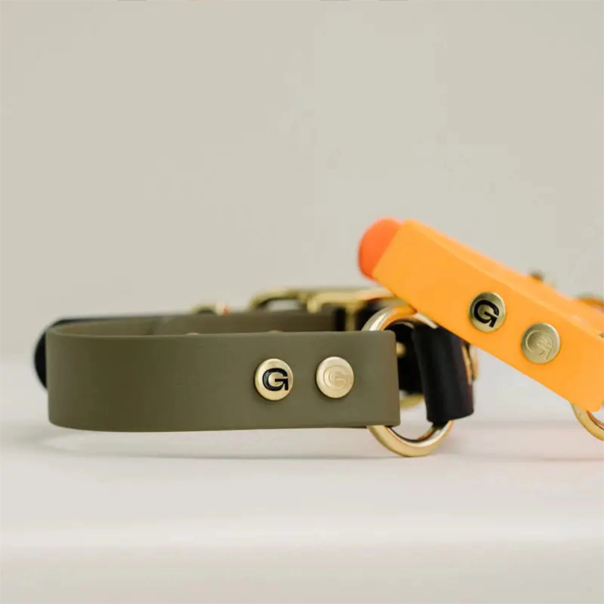 GULA Hundehalsband in Schwarz und Grün, flach liegend, mit orangefarbenen Halsband obendrauf liegend