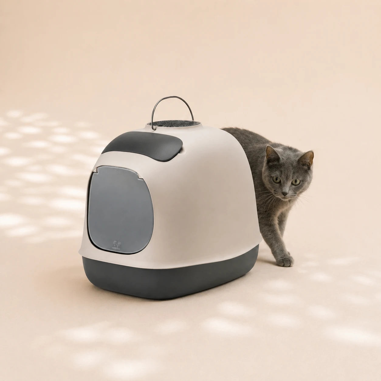 Katze hinter der Design-Katzentoilette ‚Minù‘ – modernes Katzenklo in schwarz/grau mit integriertem Filter.