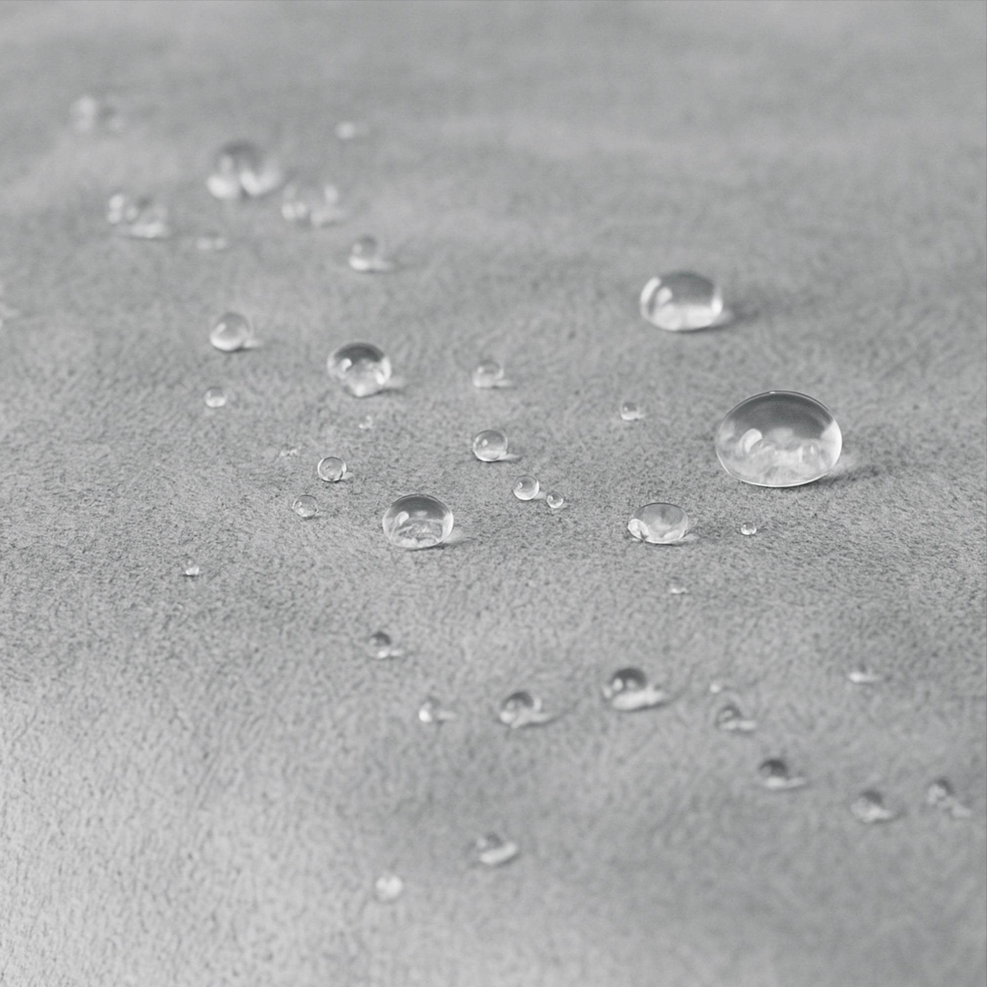 Detailaufnahme Wasserabweisung – Tropfen auf grauem Stoff des Hundebetts.