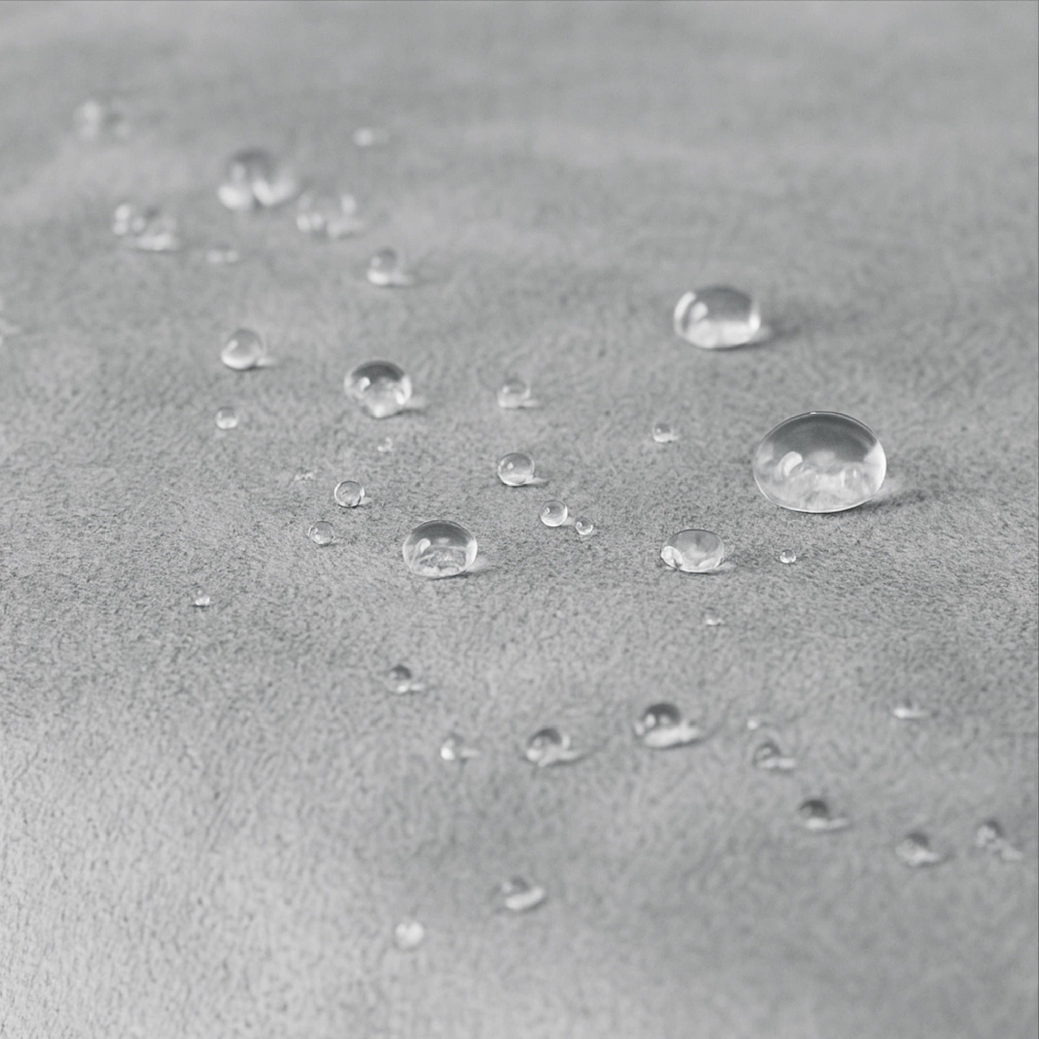 Detailaufnahme Wasserabweisung – Tropfen auf grauem Stoff des Hundebetts.